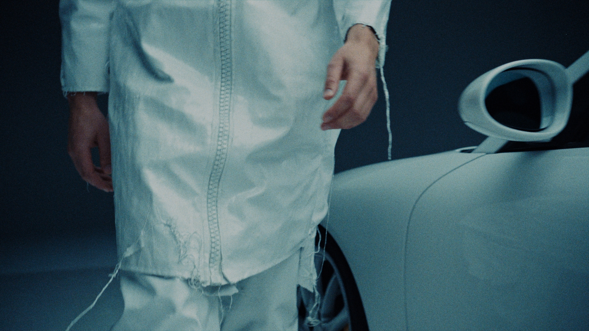 Model walking with white outfit next to a Porsche car.