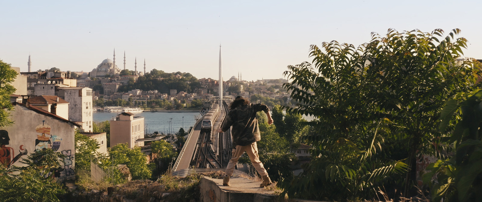 Robin-Schulz-Ft-Wes-Alane-dance-bridge-by-Robert-Wunsch Girl dancing on a rooftop with a view of a city bridge.