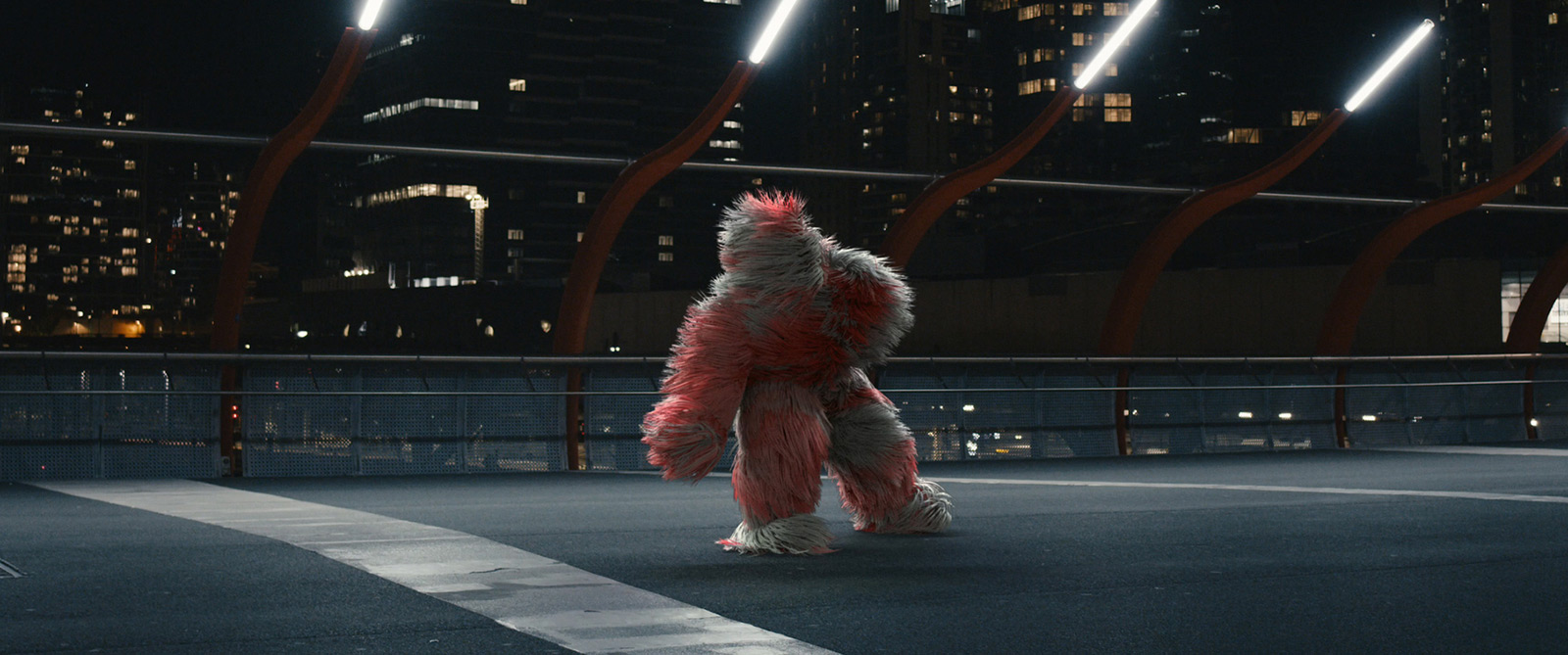 Robin-Schulz-Ft-Wes-Alane-dance-highway-by-Robert-Wunsch Red-grey fluffy figure dancing on a highway by apartments at night.